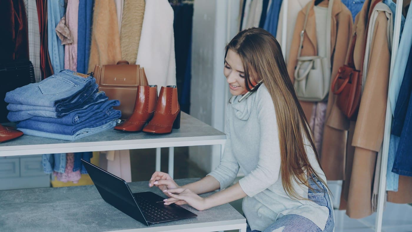 Proprietară de magazin de haine care lucrează la laptop